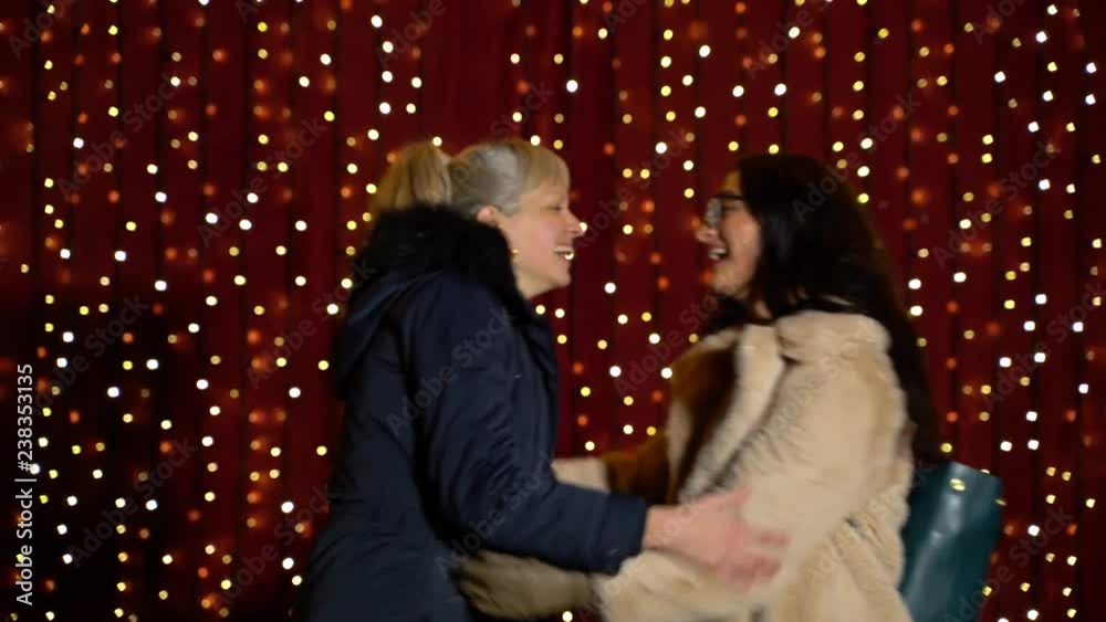 Friends meeting in front of light wall at Christmas market. Friends meeting in front of light wall at Christmas market.