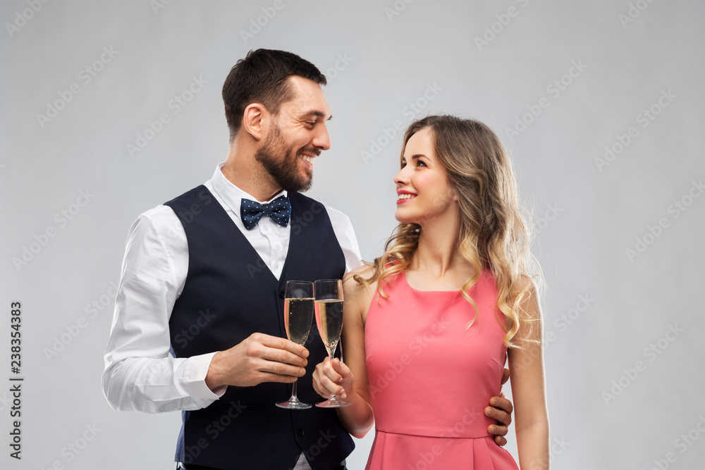 celebration and people concept - happy couple with champagne glasses toasting over grey background