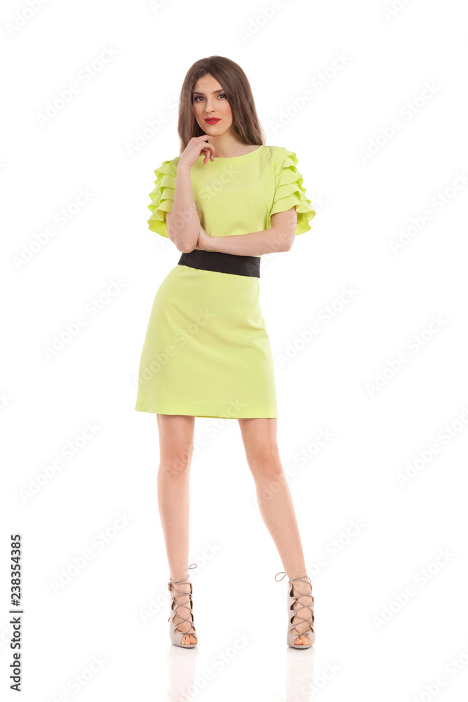 Woman In Lime Green Dress And High Heels Is Posing With Hand On Chin Woman In Lime Green Dress And High Heels Is Posing With Hand On Chin