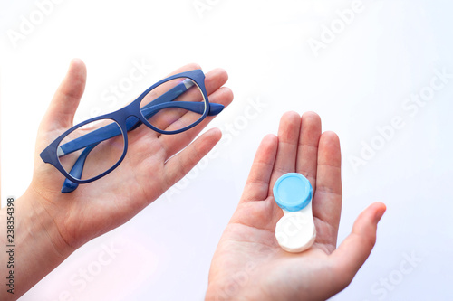female hands holding spectacles and contact lenses and choosing