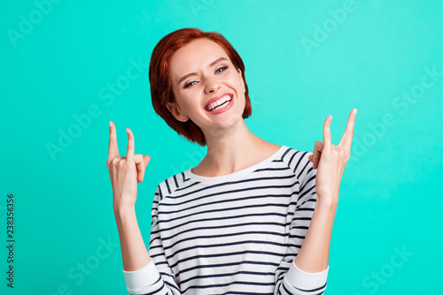 Portrait of her she lovely cool trendy stylish attractive cheerful red-haired lady wearing striped pullover showing two double horns isolated over bright vivid shine turquoise background