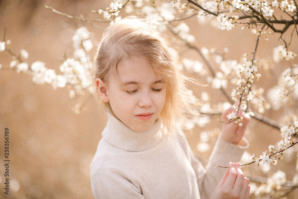 Blonde girl in the blossom garden. Spring background with white flower Blonde girl in the blossom garden. Spring background with white flower