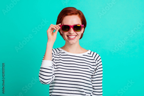 Close up portrait of attractive she her lady holding hand on red dark summer glasses before rest vacation wearing white striped sweater isolated on teal background