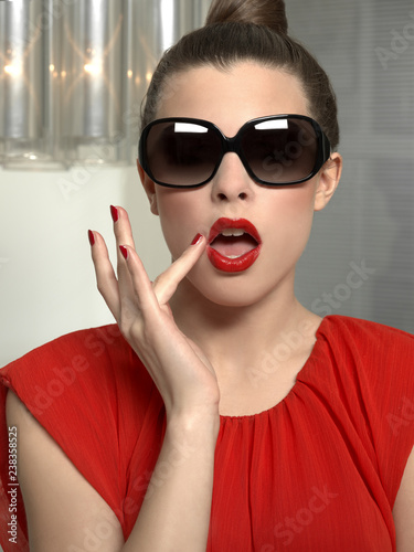 woman with red lips and red shirt tuching her mouth