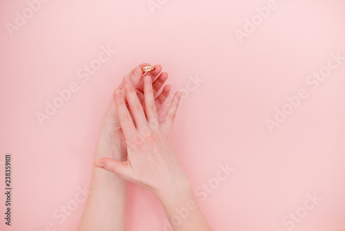 Female hands with a golden ring. Marriage and divorce concept. Top view horizontal one object. Light pink background.