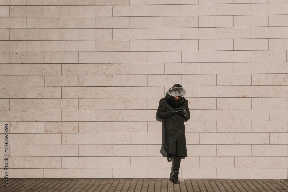 Black man standing near brick wall with mobile phone Black man standing near brick wall with mobile phone
