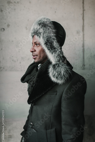 Side view of man in ushanka standing near concrete wall photo