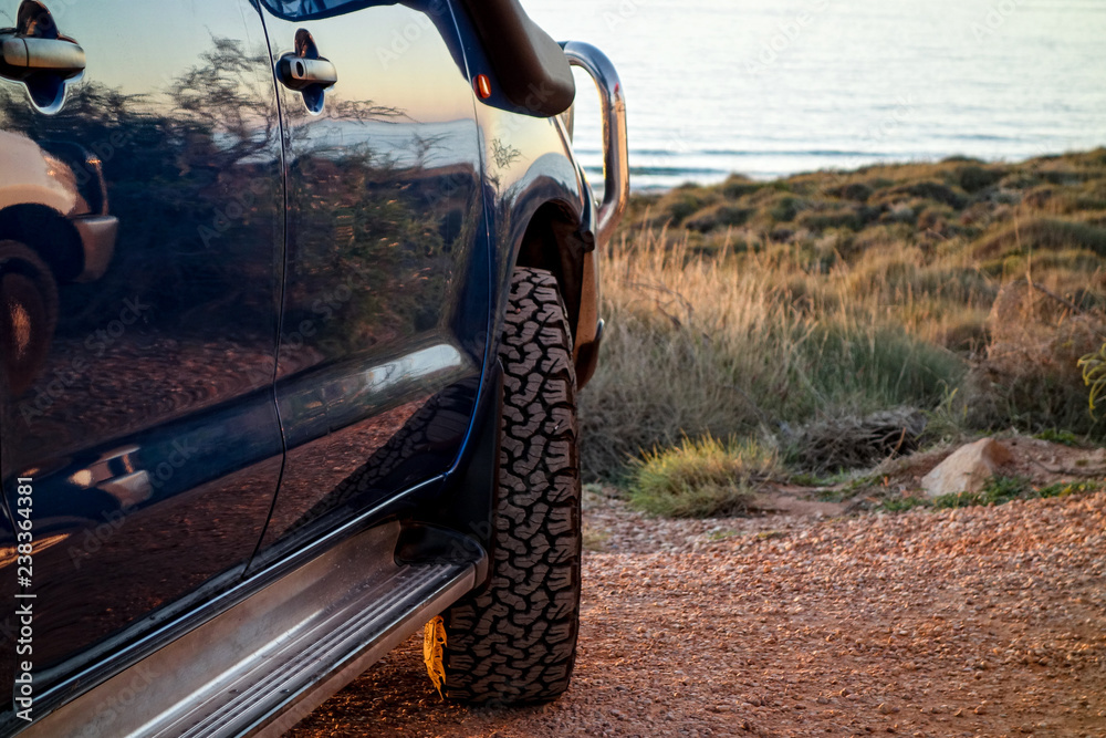 Naklejka premium A blue modern SUV with off-road tyres parked near the ocean in Western Australia