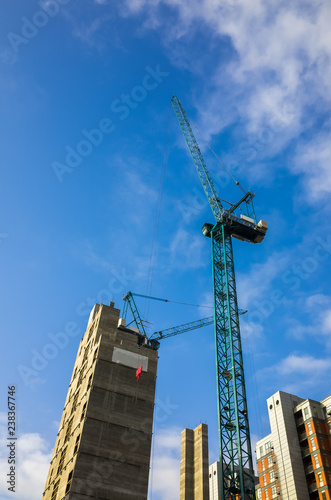 Tall crane operating on a construction site of high-rise apartments in the city of Leeds, England, UK. Construction, Development, Cranes and Building concepts