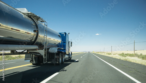 truck with a silver tank trailer passing a passenger car on a highway