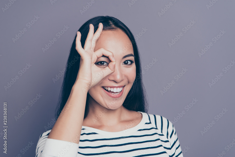 Close-up portrait of her she nice cute attractive lovely positive cheerful optimistic straight-haired lady in striped pullover sweater showing like glasses one eye isolated over gray pastel background Close-up portrait of her she nice cute attractive lovely positive cheerful optimistic straight-haired lady in striped pullover sweater showing like glasses one eye isolated over gray pastel background
