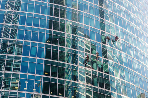 A group of industrial climbers cleaning windows service on skyscraper. Workers on the heights, industrial mountaineering