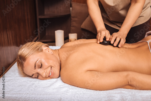 Delighted happy woman enjoying the stone massage