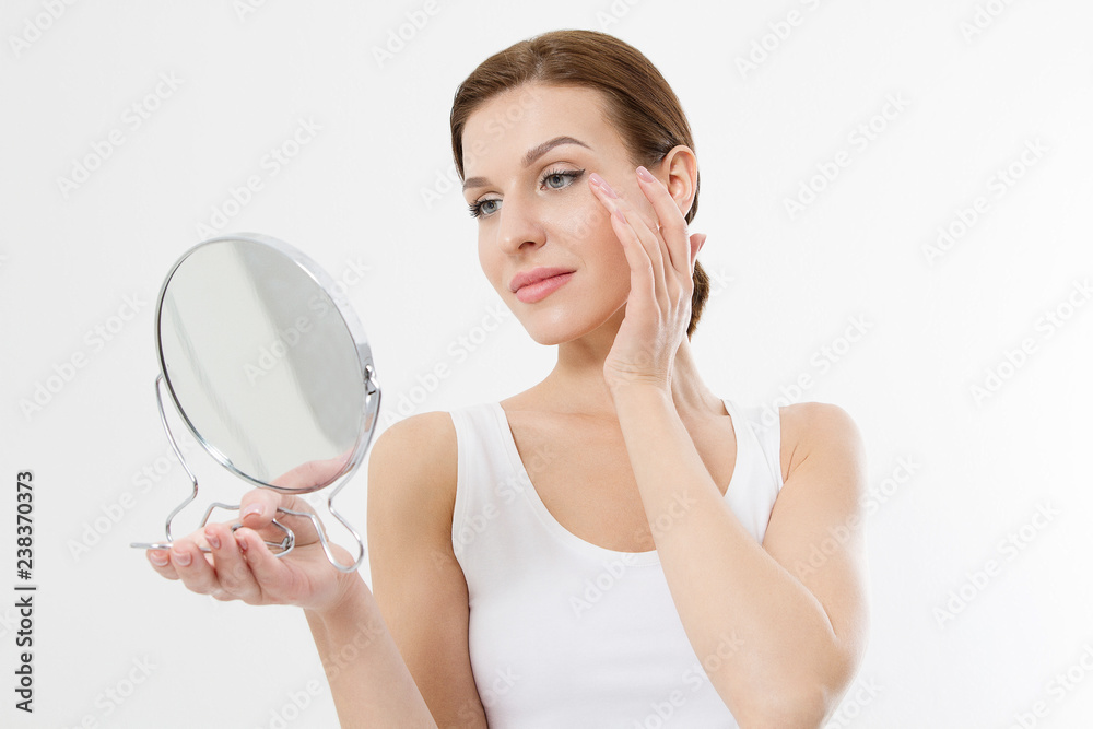 Smiling young woman with white teeth looking in mirror isolated on white background. Skin care and anti aging concept. Beauty and body health. Copy space
