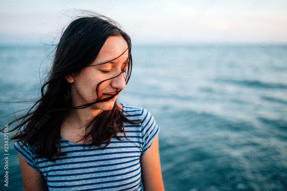 Portrait of a young woman with closed eyes and hair on her face at the sand sea beach Portrait of a young woman with closed eyes and hair on her face at the sand sea beach
