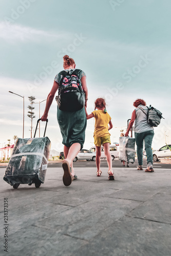 A woman with a child migrants arrived in a foreign country. They go quickly with luggage