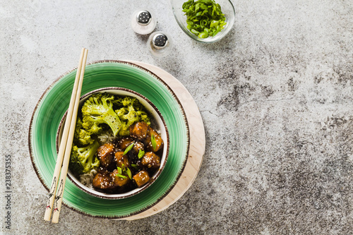 Basmati rice with tofu in General Tso sauce and steamed broccoli. full healthy vegetarian lunch or dinner on a stone table photo