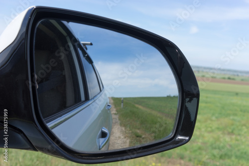 Car mirror on a background of green fields.