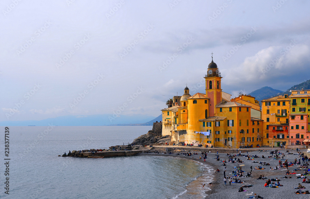  colorful buildings, church and architecture with crowd of people on the beach in picturesque village Camogli in liguria, nothern italy