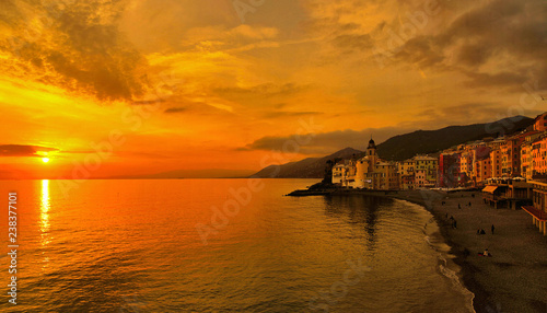 panorama with colorful warm orange sunset and old buildings and church in camogli village and beach in liguria  nothern italy