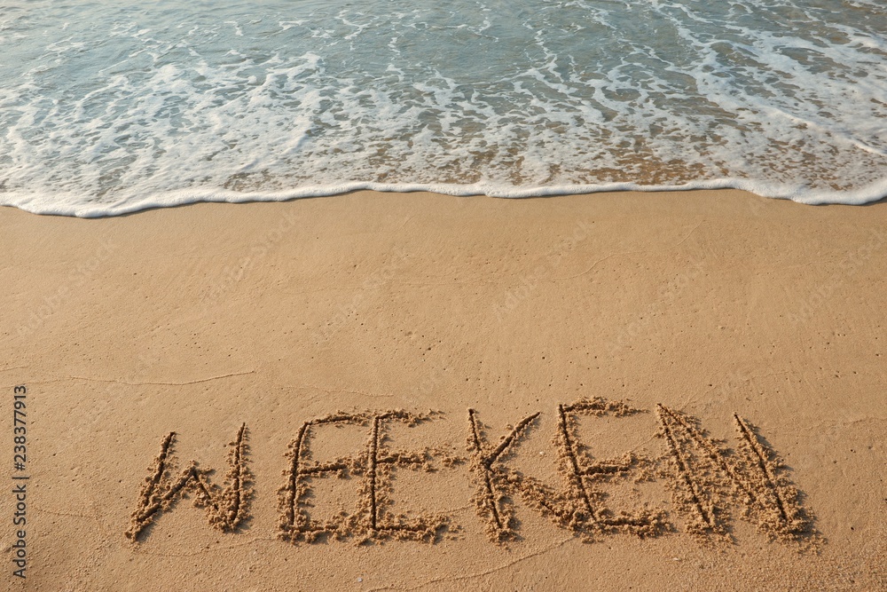 Fototapeta premium The word concept, WEEKEN handwriting on sand beach.