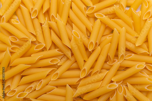 dry yellow pasta on the table, top view as background