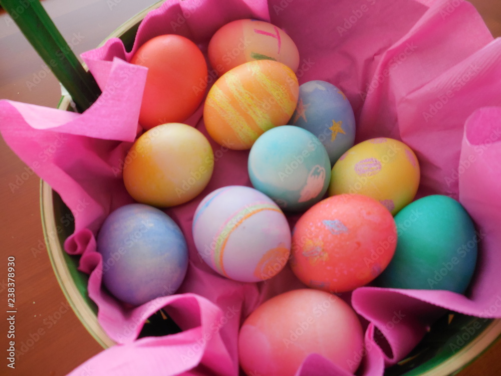 Colored Easter eggs in pink basket from above Colored Easter eggs in pink basket from above