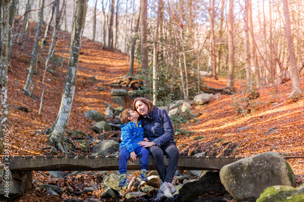 Mother and son sitting on a bridge in autumn Mother and son sitting on a bridge in autumn