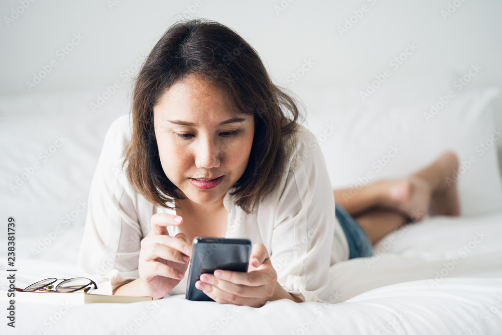 Beautiful Asian girl sleeping on a smartphone. Play on the media. Talk to a friend or comments in the Internet communication by mobile phone. Work through phone Working outside the office
