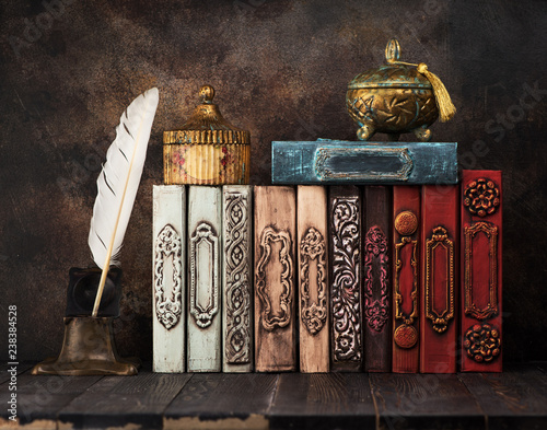 Vintage books on a shelf, ancient caskets, manuscript and antiquarian inkwell with a feather. Retro still life photo
