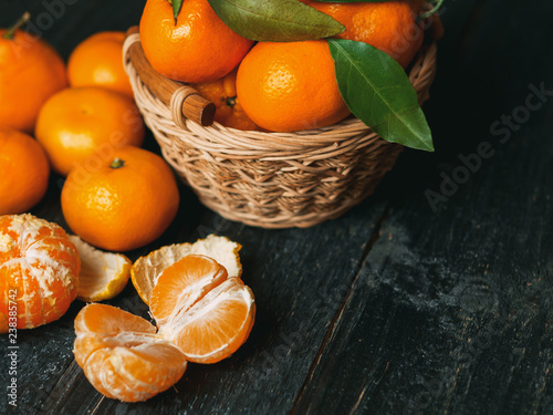Tangerines in a wooden basket on a dark wooden table