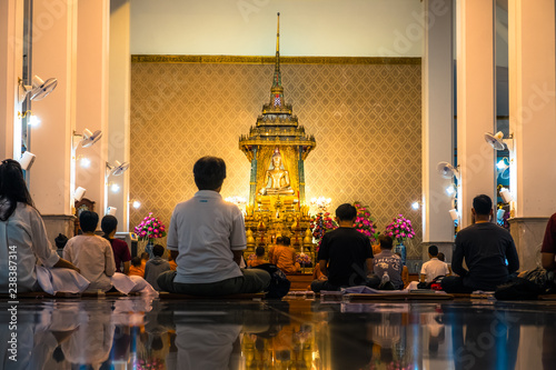 Night scene of people meditating in the temple. Wat Pathum Wanaram temple, Bangkok, Thailand.