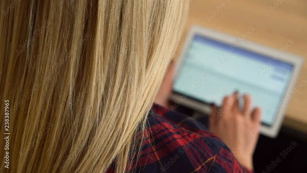 Blonde-haired woman texting on tablet pc, using social media, typing email Blonde-haired woman texting on tablet pc, using social media, typing email