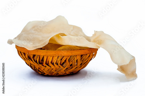 Popular Indian and Asian crispy snack dish i.e. Raw uncooked Papad or rice flour papadum in  a hamper isolated on white. photo