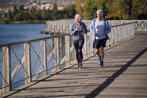  Active senior couple jogging together on bridge