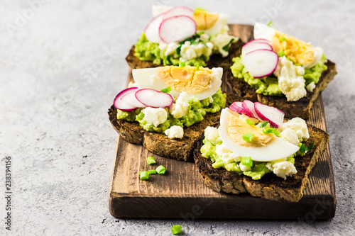 Avocado radish eggs bruschetta on cutting board. Selective fcous, space for text. photo