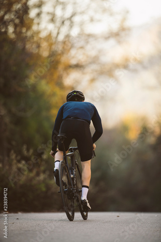 A side shot of a professional slim cyclist riding up a mountain