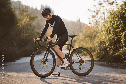 Professional road bicycle racer posing. Men cycling mountain road bike at sunset.
