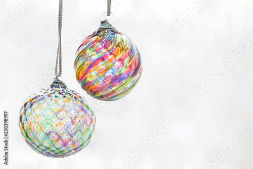 Photograph of two glass blown Christmas tree ornaments suspended against a white background photo