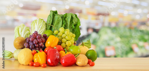 Fresh fruits and vegetables on wood table with supermarket grocery store blurred defocused background