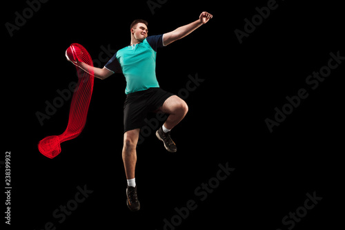 The fit caucasian young male handball player at studio on black background. Fit athlete isolated on black with led light trail . The man in action, motion, movement. attack and defense concept