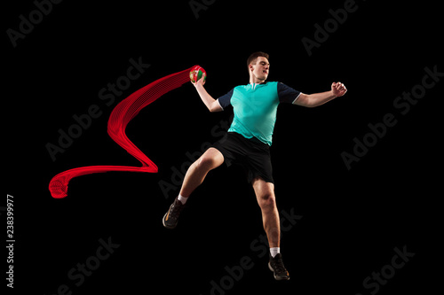 The fit caucasian young male handball player at studio on black background. Fit athlete isolated on black with led light trail . The man in action, motion, movement. attack and defense concept