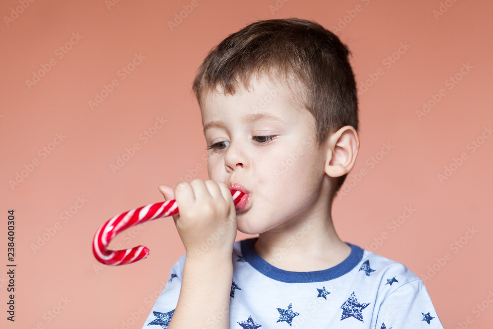 A cute boy eating candy sticks. Colored traditional handmade candy canes A cute boy eating candy sticks. Colored traditional handmade candy canes