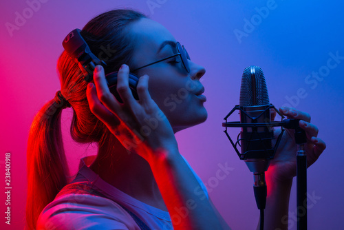 Fotografija music, show business, people and the voice of a singer or DJ with headphones with glasses and a microphone singing a song in the recording studio