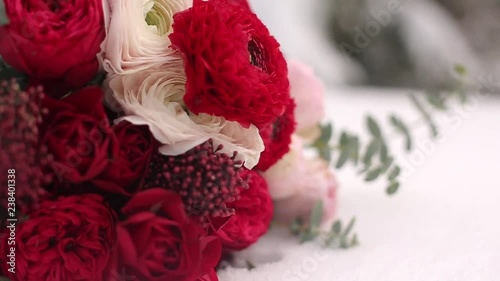 Wedding bouquet of red and white flowers on snow in evergreen conferous woods. Close and macro view of tender roses on snowy surface during snowfall in spruce winter forest. photo