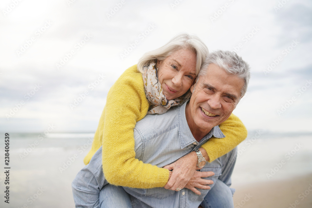 Obraz premium Loving portrait of attractive senior couple on beach in fall