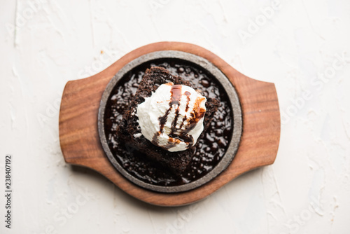Foto sizzling chocolate brownie is a sweet dish made using scoop of ice-cream on top served with a generous pouring of melted chocolate
