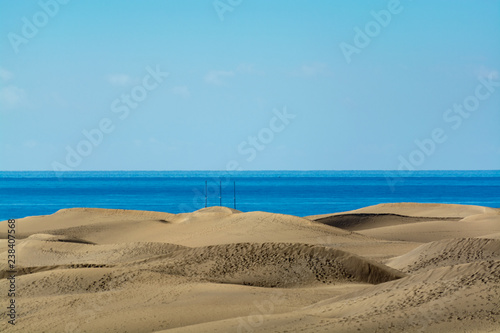 Landscape with yellow sandy dunes of Maspalomas and blue Atlantic ocean, Gran Canaria, Spain