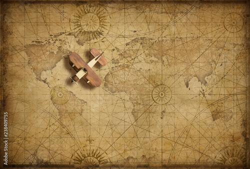Small wood airplane over world nautical map as travel, explore and communication concept