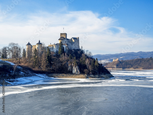 Medieval castle in Niedzica, Poland, in winter at partially frozen artificial Czorsztyn lake on Dunajec river and the far view of Czorsztyn castle. Sunset light © kilhan
